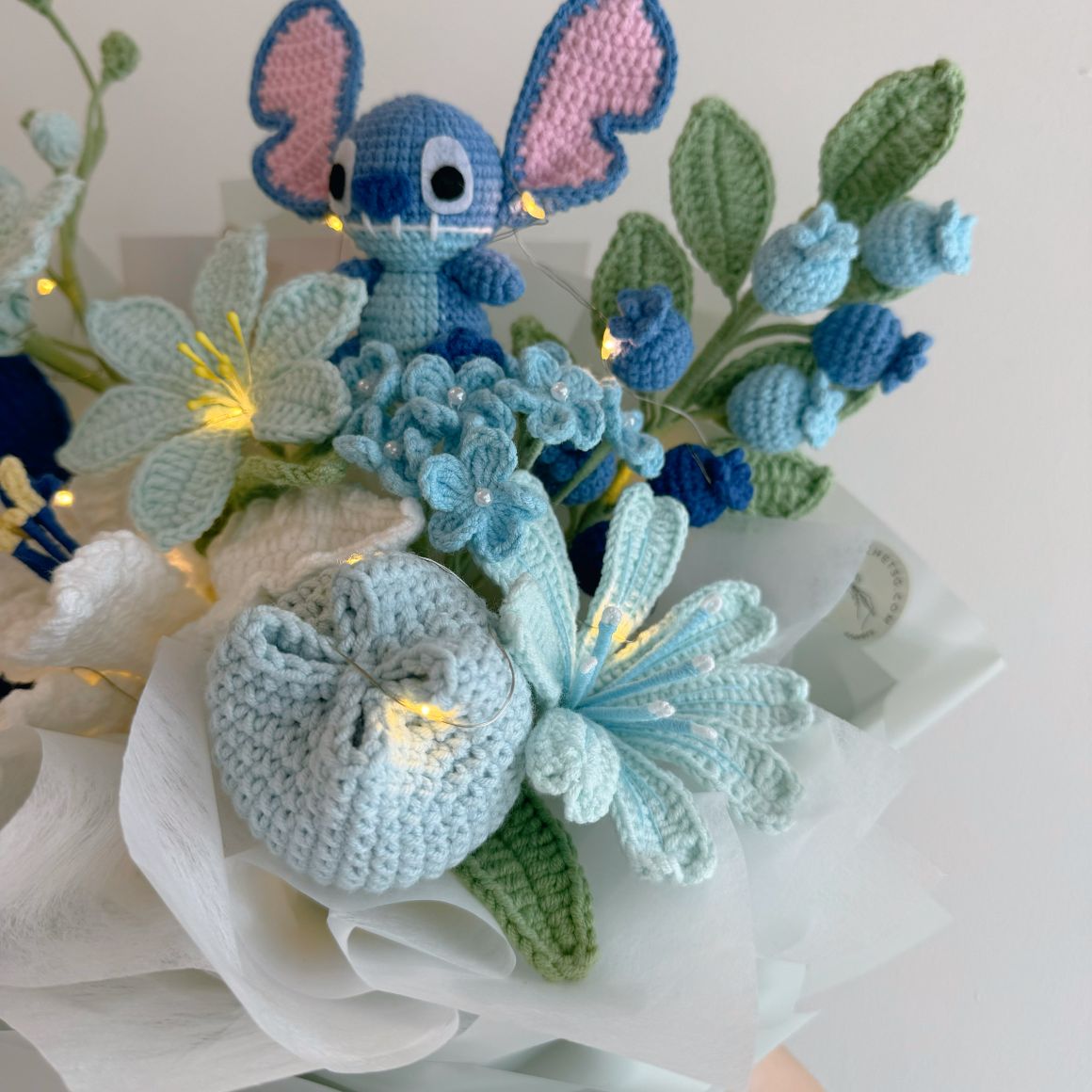Crocheted character with a bouquet of flowers on a white background