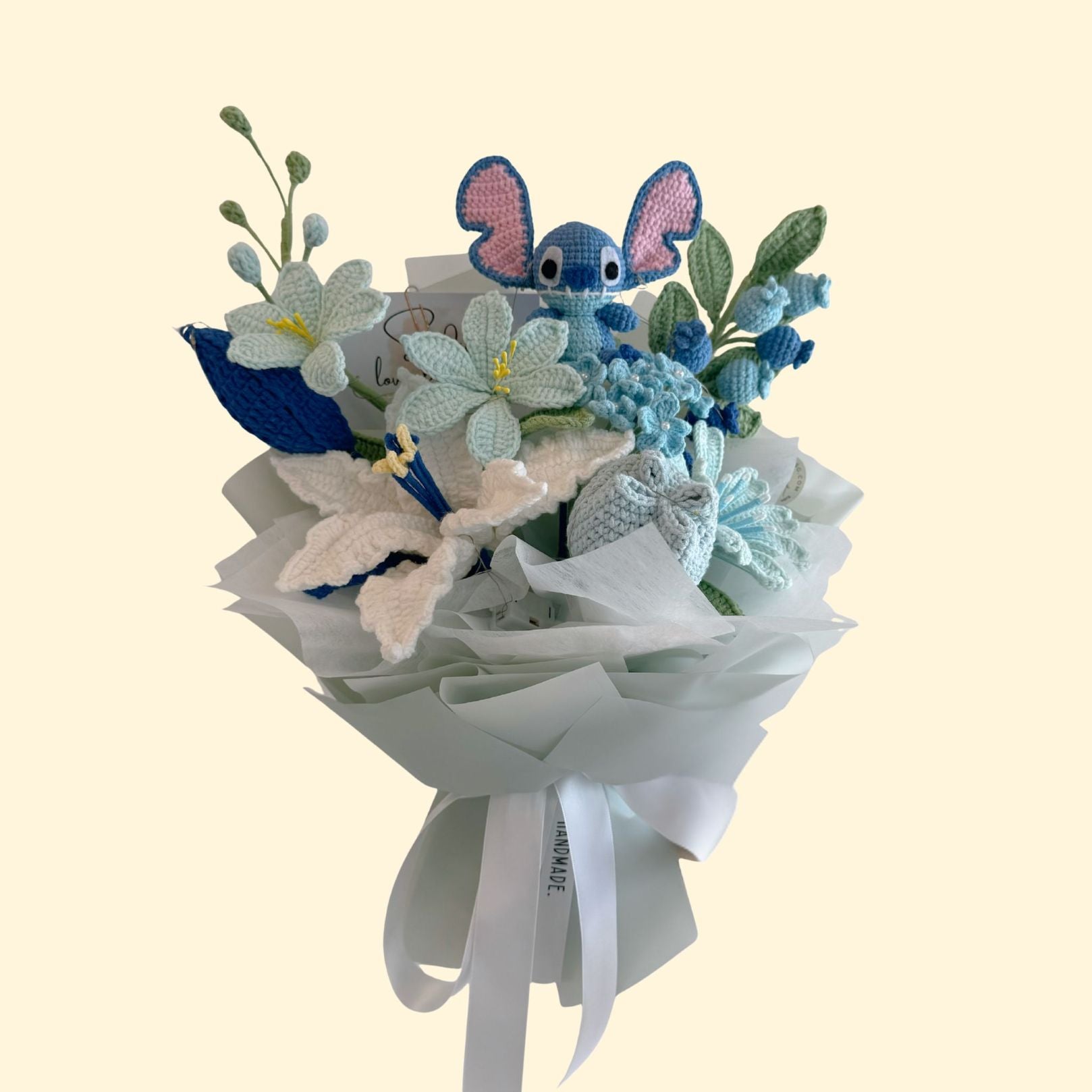 Bouquet with knitted blue elephants and flowers on a light beige background