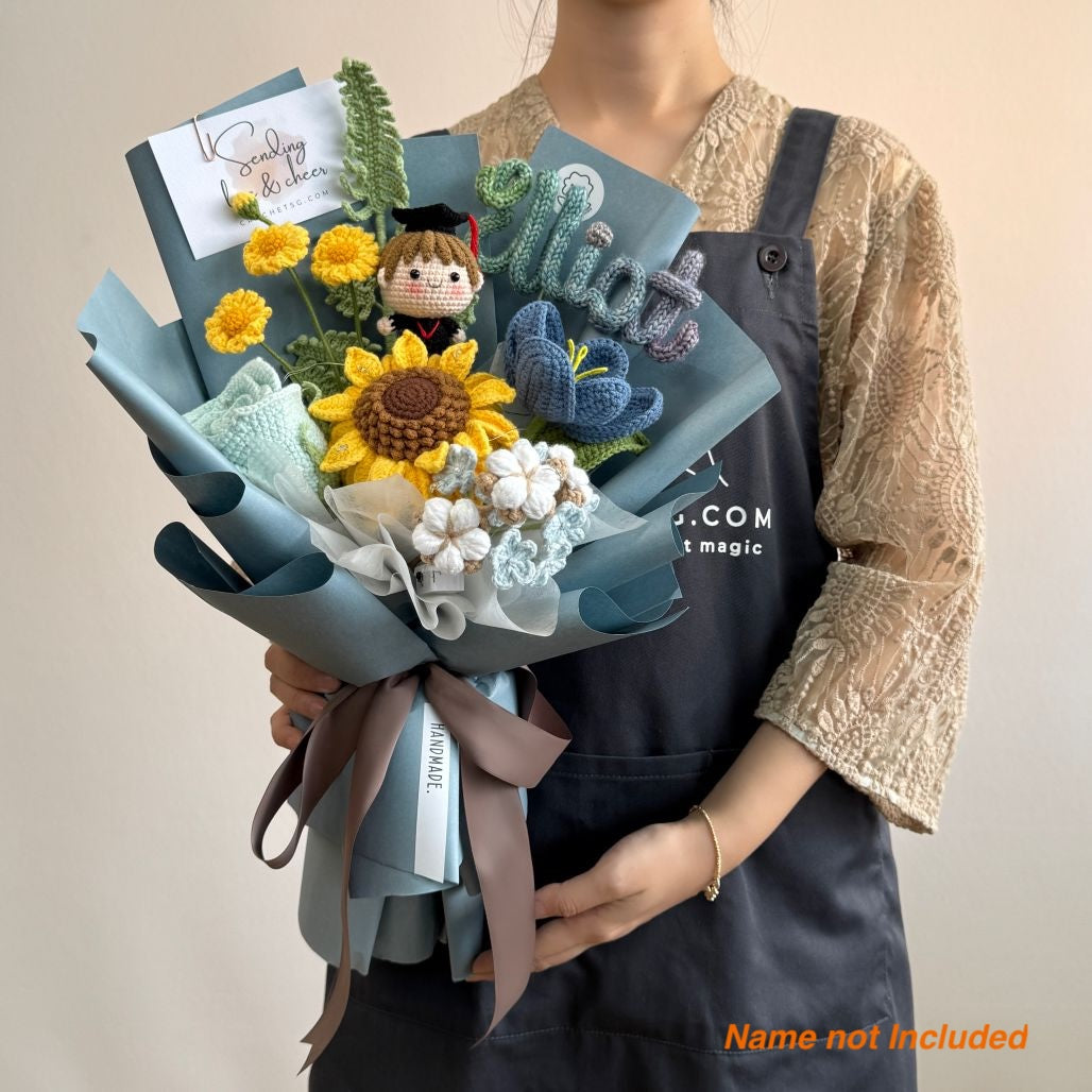 Person holding a bouquet with decorative elements and a card, against a plain background.