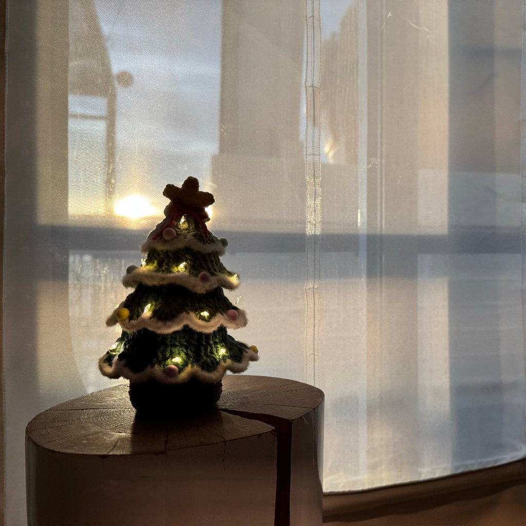 Lighted Crochet Christmas Tree in a dark room setting against the sun set background