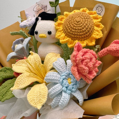 Bouquet of crocheted flowers with a small crocheted duck toy in the center.