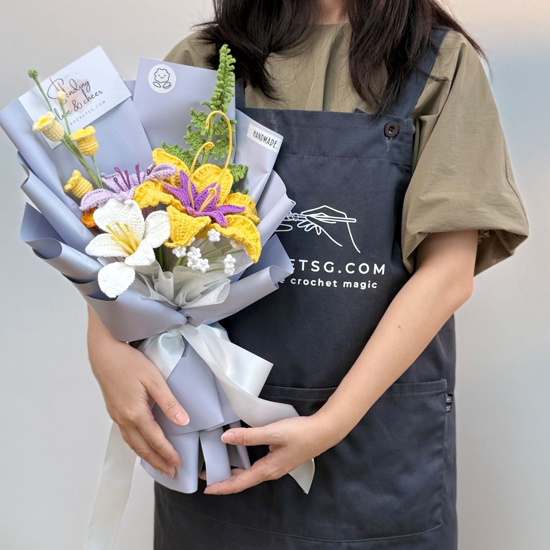 Person holding a bouquet of flowers wearing an apron with 'TSG.com' branding.