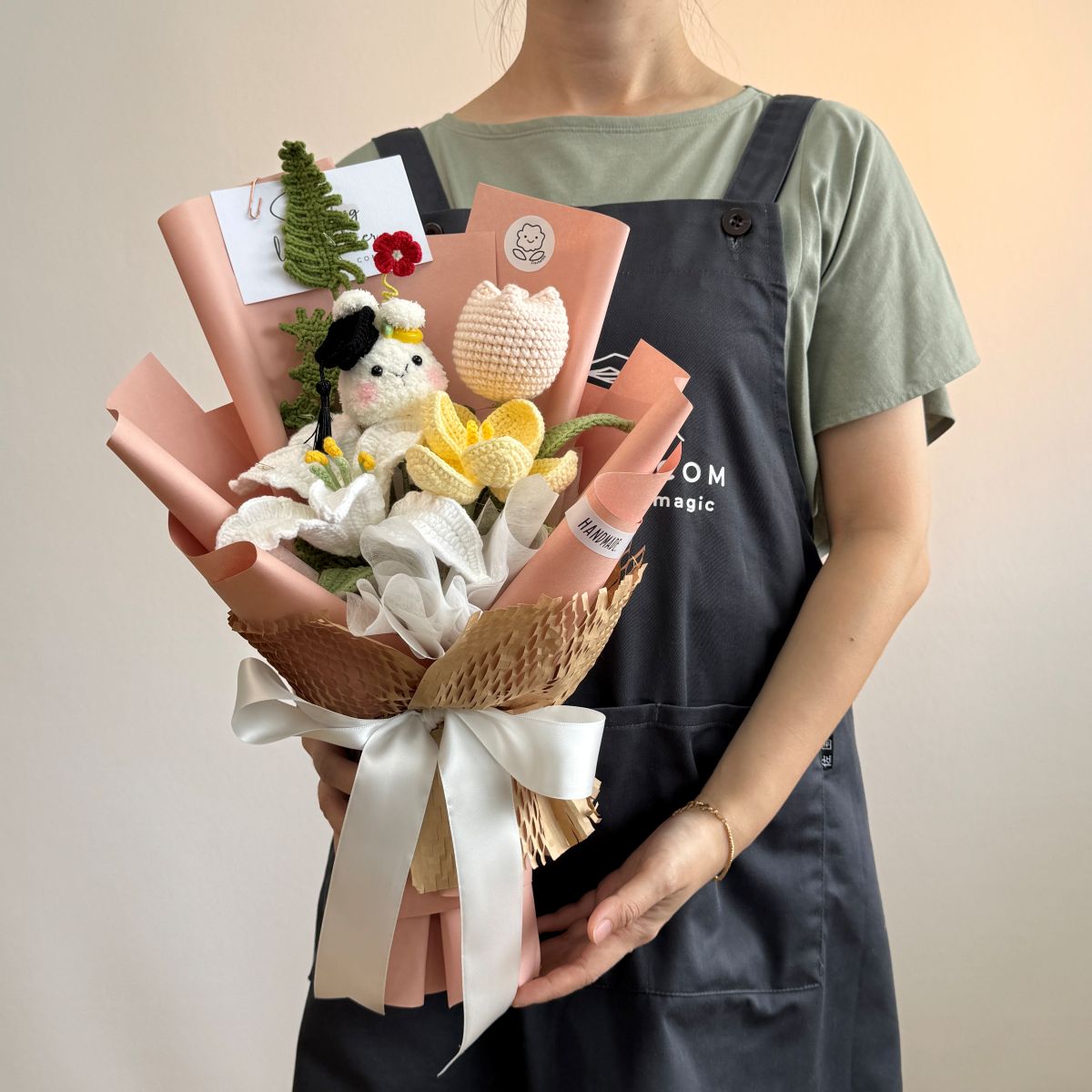 Person holding a bouquet with a plush toy, books, and a small plant against a plain background