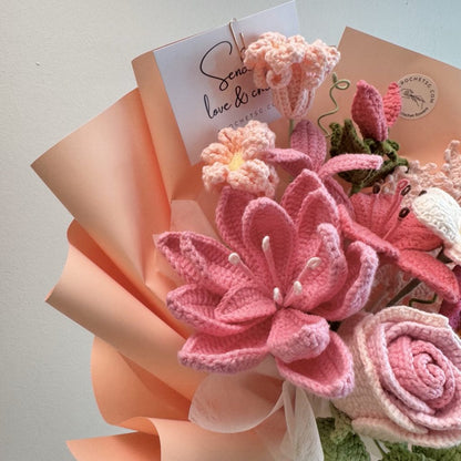 Bouquet of pink knitted flowers with a card on a light background