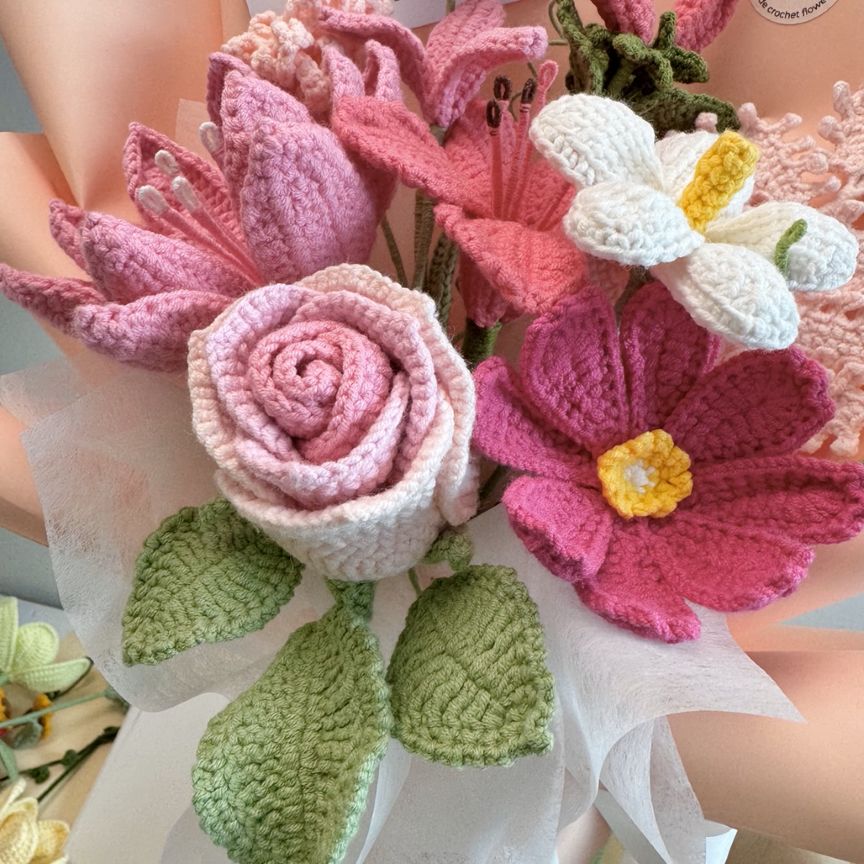 Crocheted flowers in various colors held by a person.