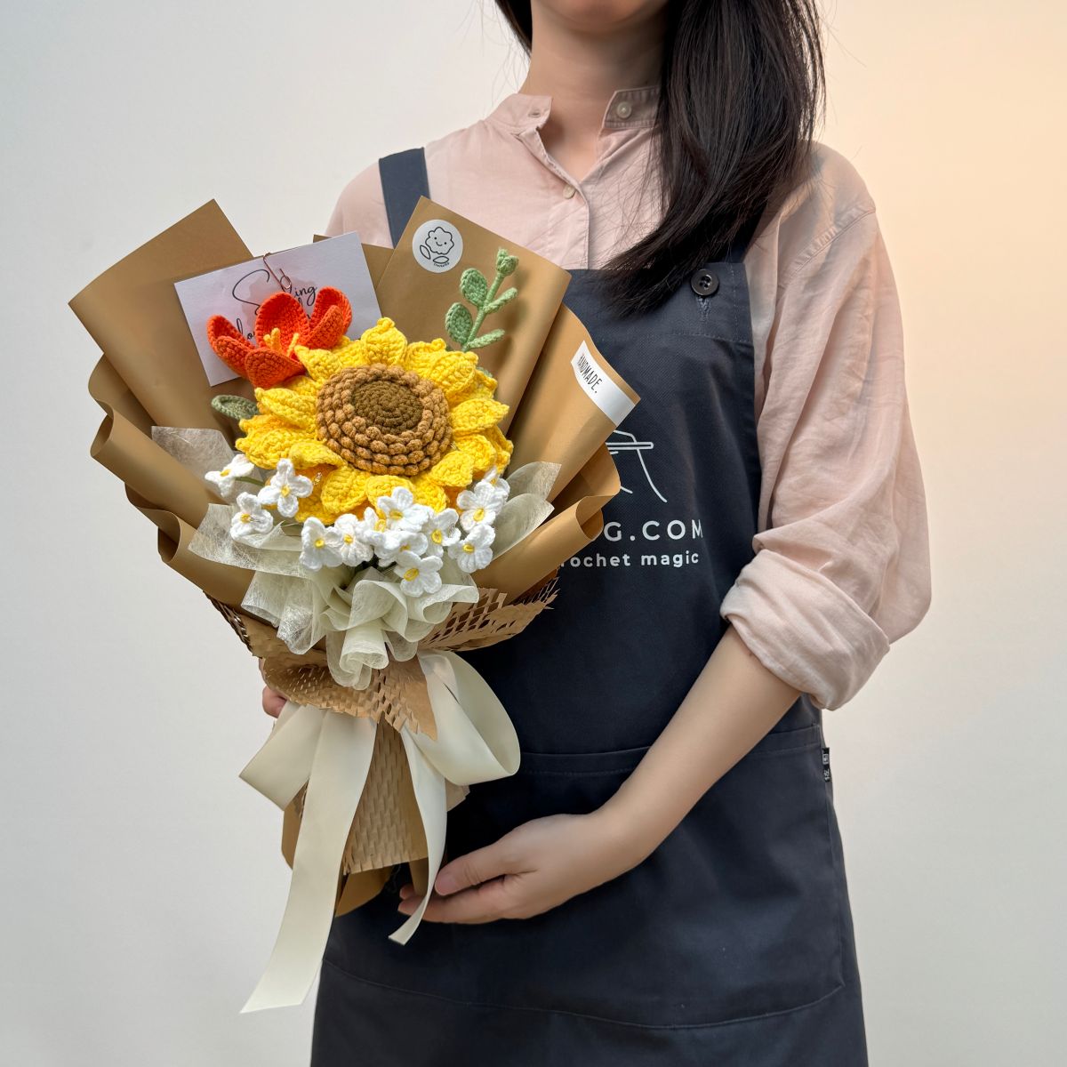 Person holding a bouquet with a sunflower design against a plain background