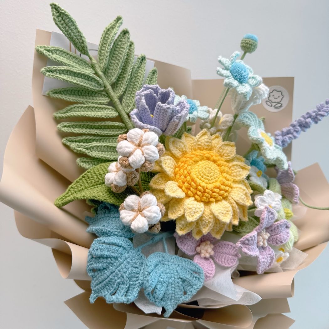 Crocheted flower bouquet with colorful flowers and leaves on a light background