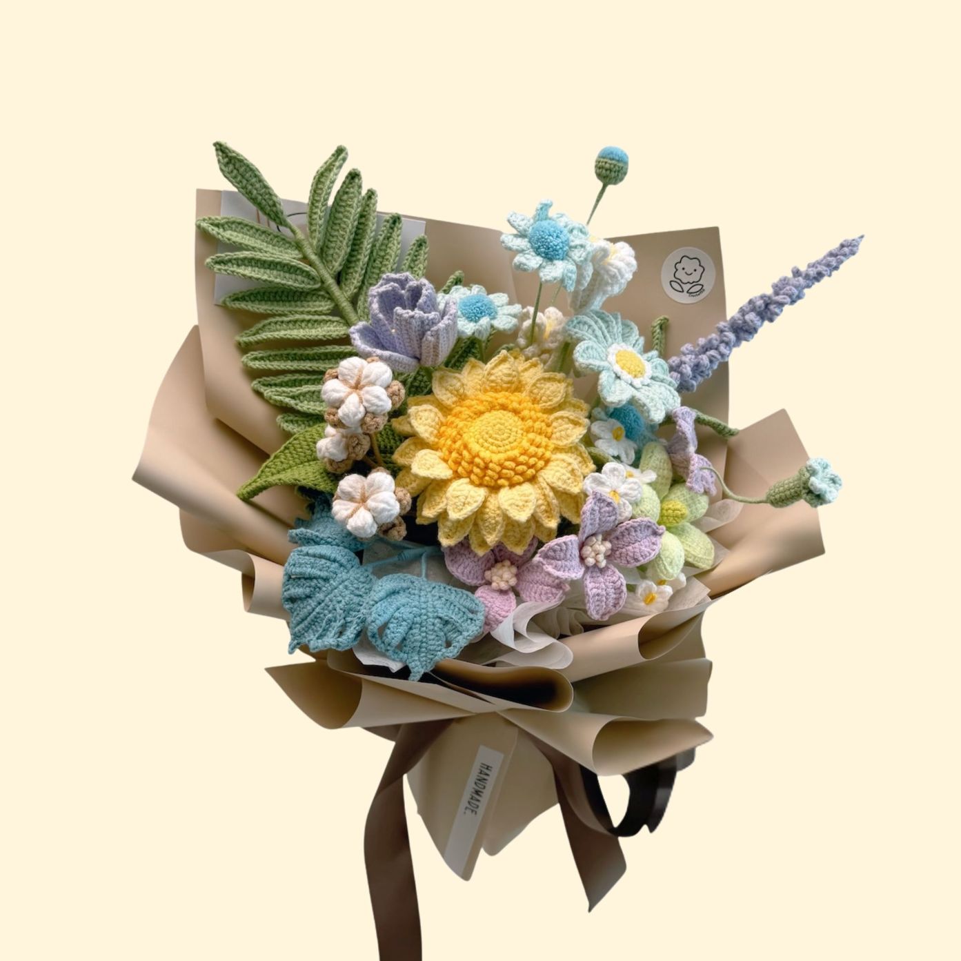 Knitted flower bouquet with a yellow center and green leaves on a beige background