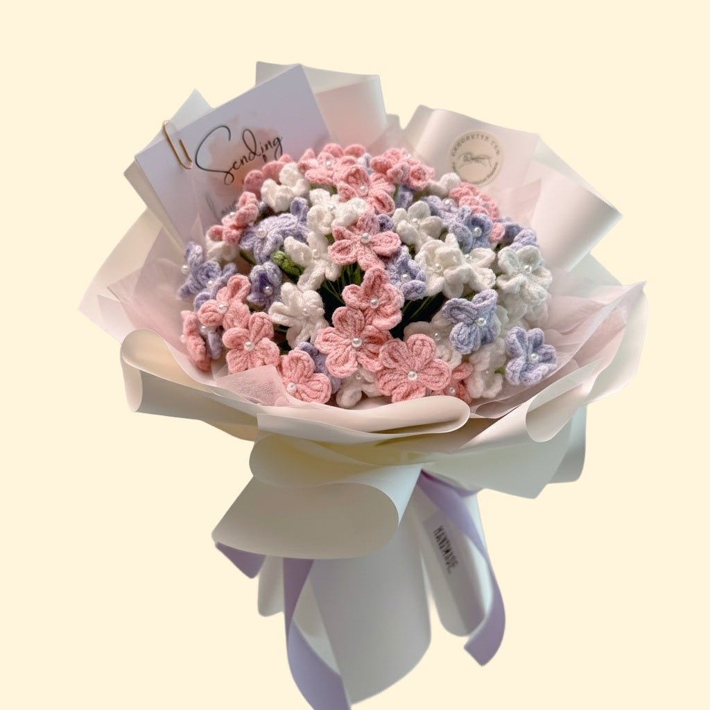 Bouquet of pink, white, and purple flowers with a white ribbon on a light beige background.
