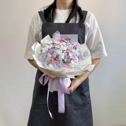 Person holding a bouquet of flowers wrapped in white paper with a pink ribbon against a plain background