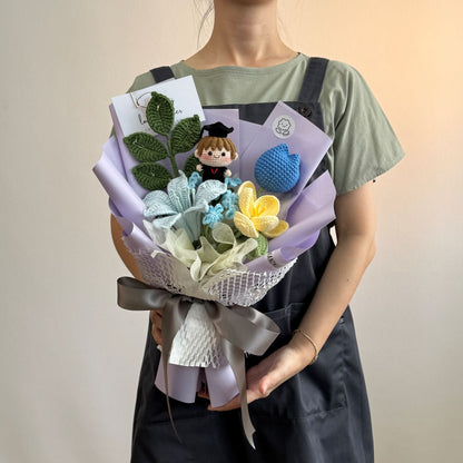 Person holding a bouquet with flowers and a small figurine on a plain background