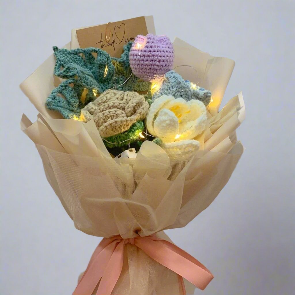 A bouquet of crochet flowers with beige garden rose, white tulip and green monsterra leaf