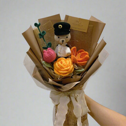 A Bouquet of crochet flowers like yellow garden rose and orange tulip with a crochet bear wearing a SPF uniform