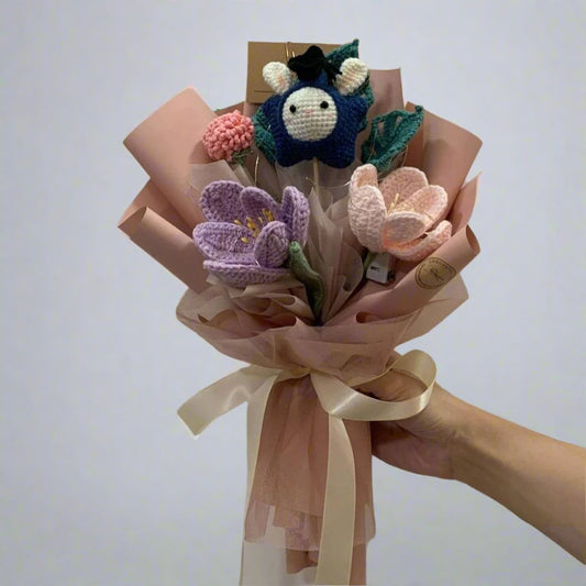 A bouquet of crochet flowers with a crochet bunny in star shaped head wear and a graduation hat